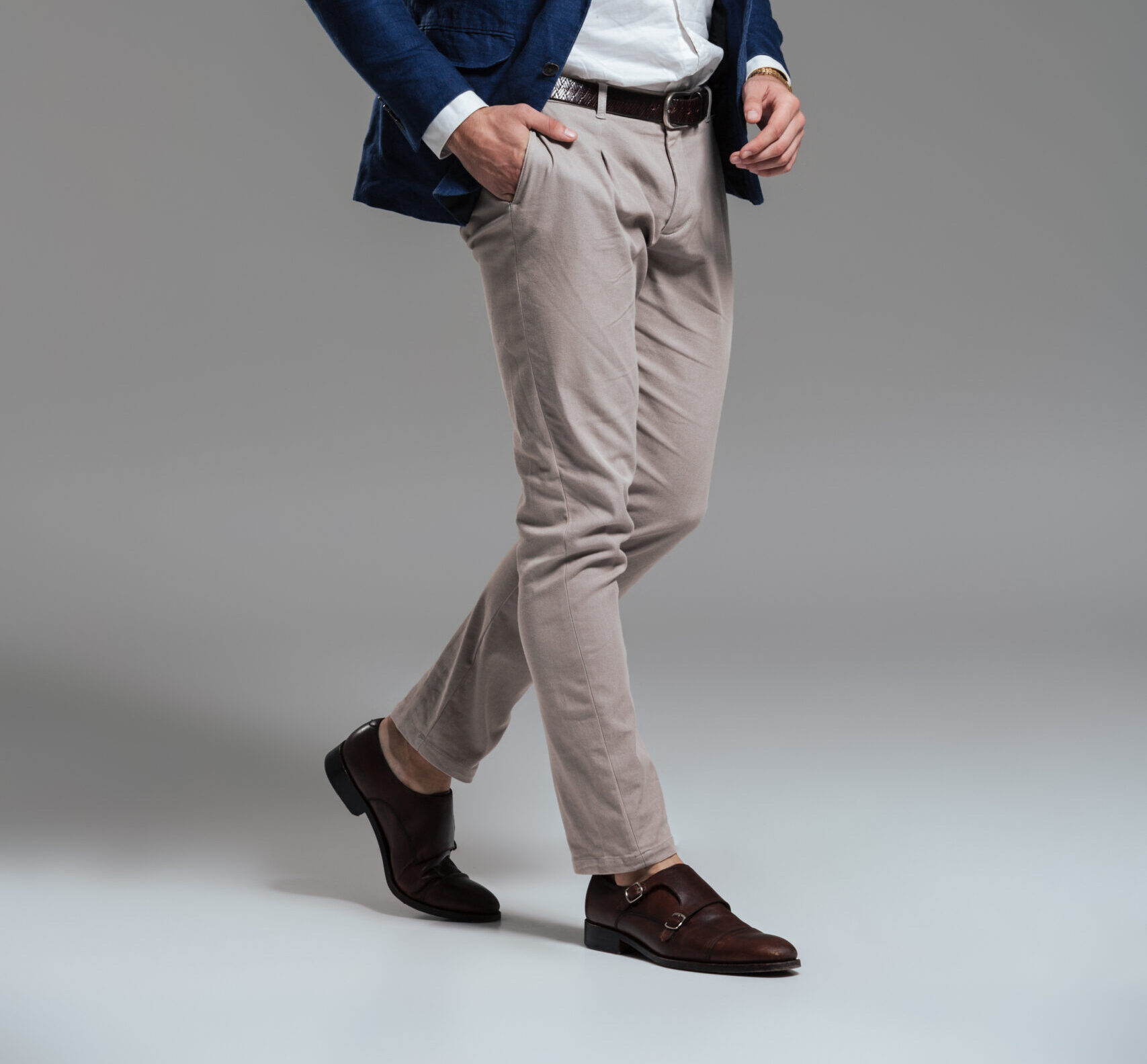 Full length portrait of a handsome serious man dressed in a jacket posing while standing and looking at camera isolated over gray background